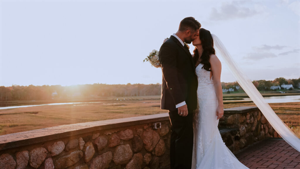 Couple kissing in front of a marsh River Club in Scituate, Massachusetts