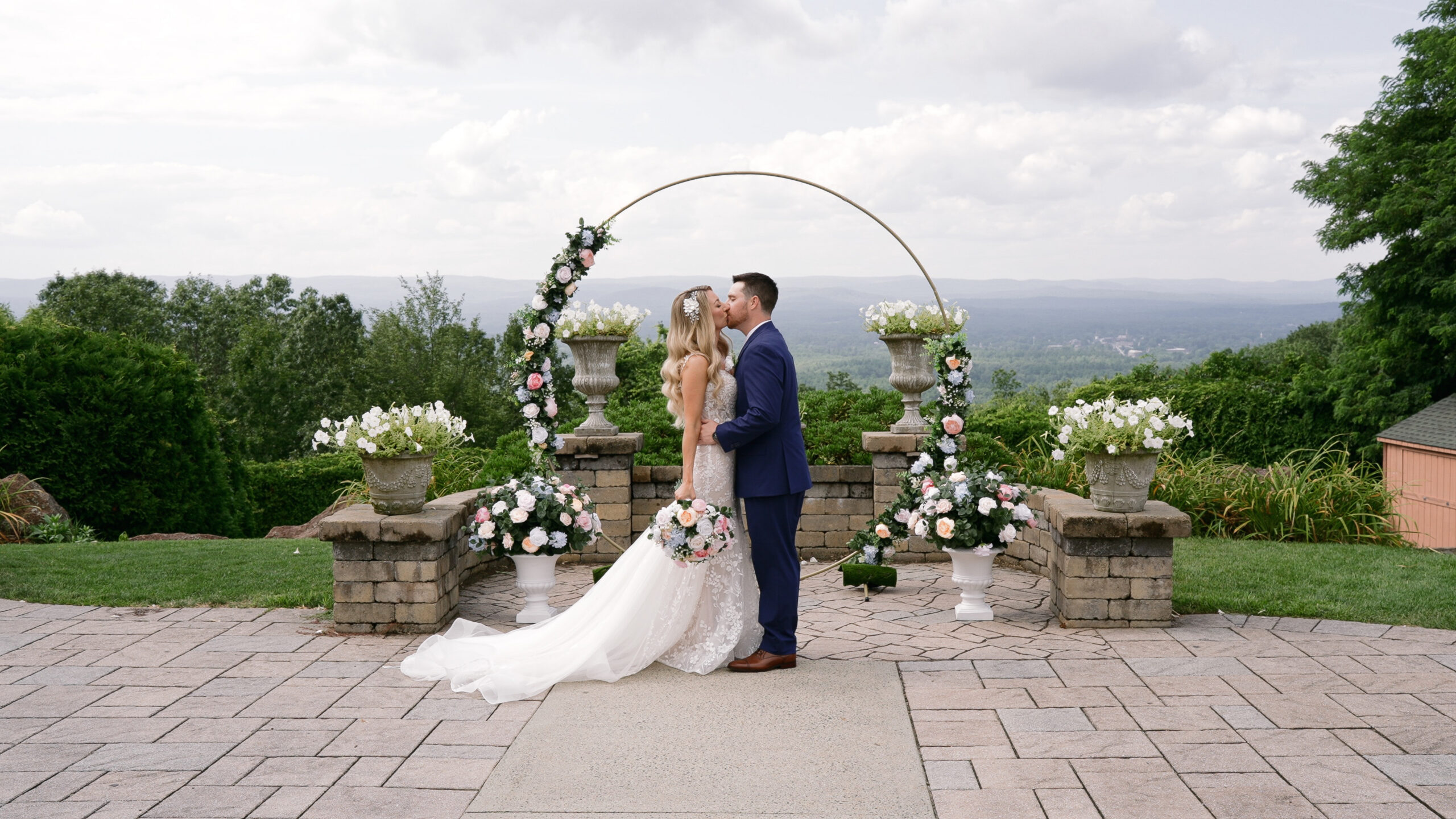 bride and groom kissing at their decorated arch.